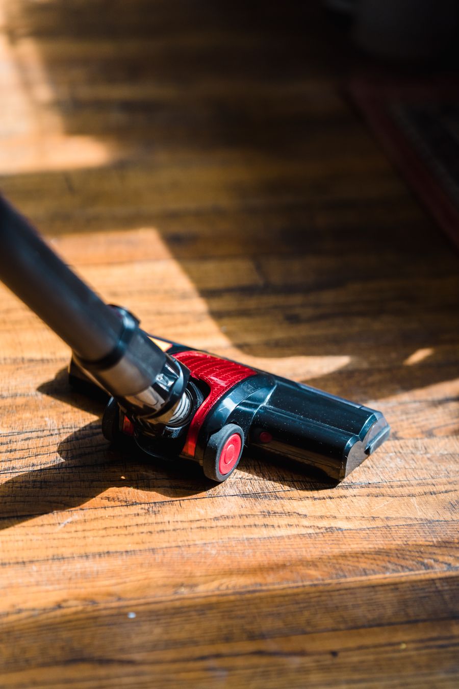 Close-up of a generic vacuum head on a wooden floor for corded stick vacuum buying advice