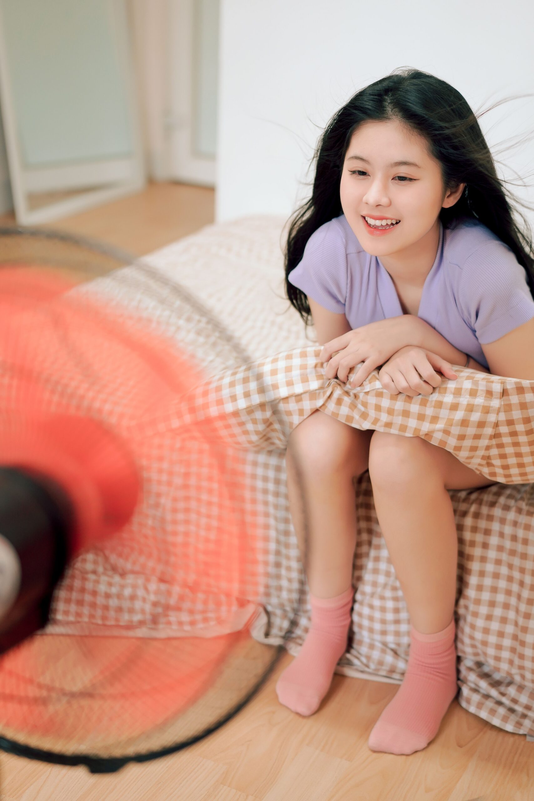 Person enjoying airflow from a pedestal fan in a bedroom