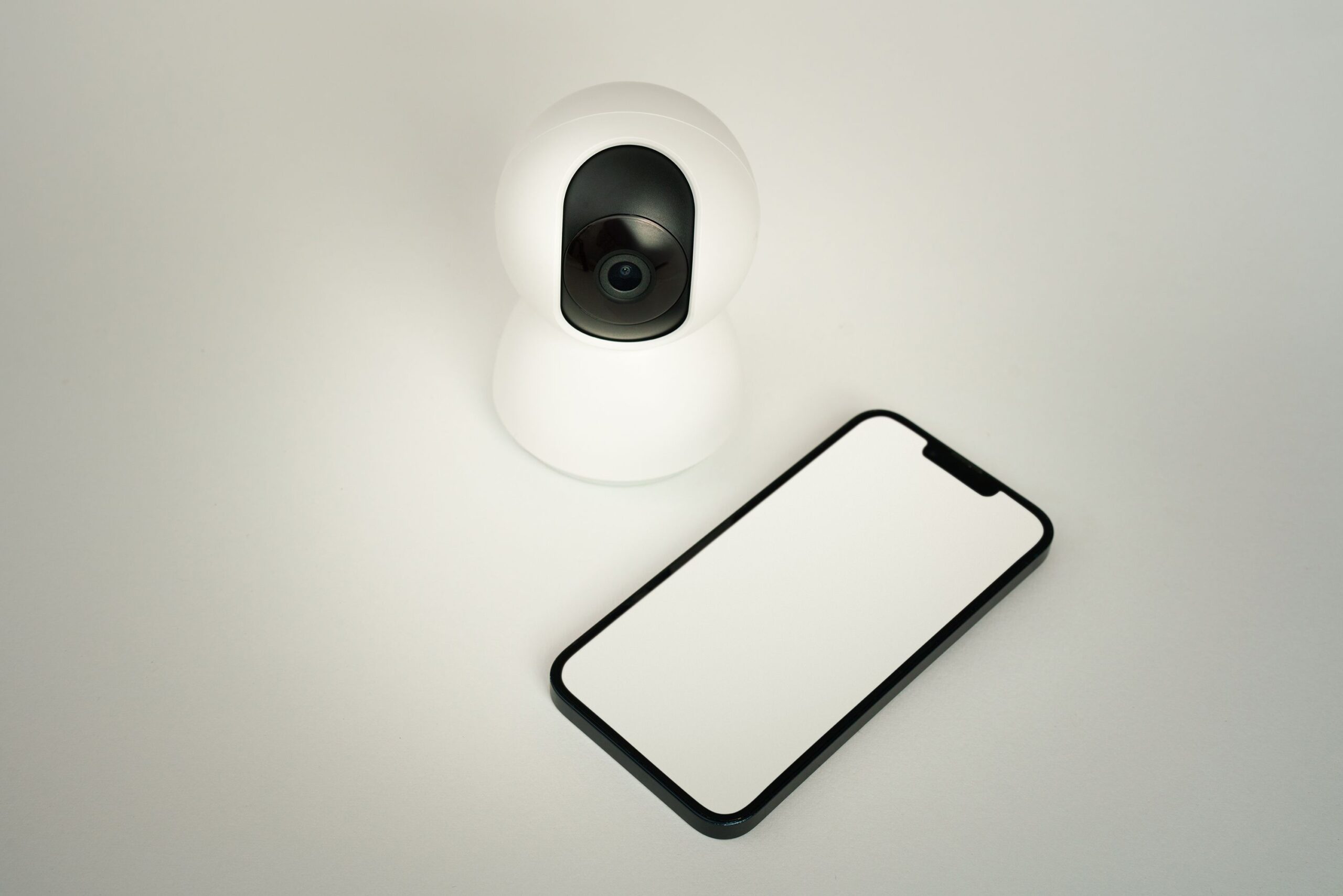 Smart security camera beside a smartphone representing remote video doorbell monitoring