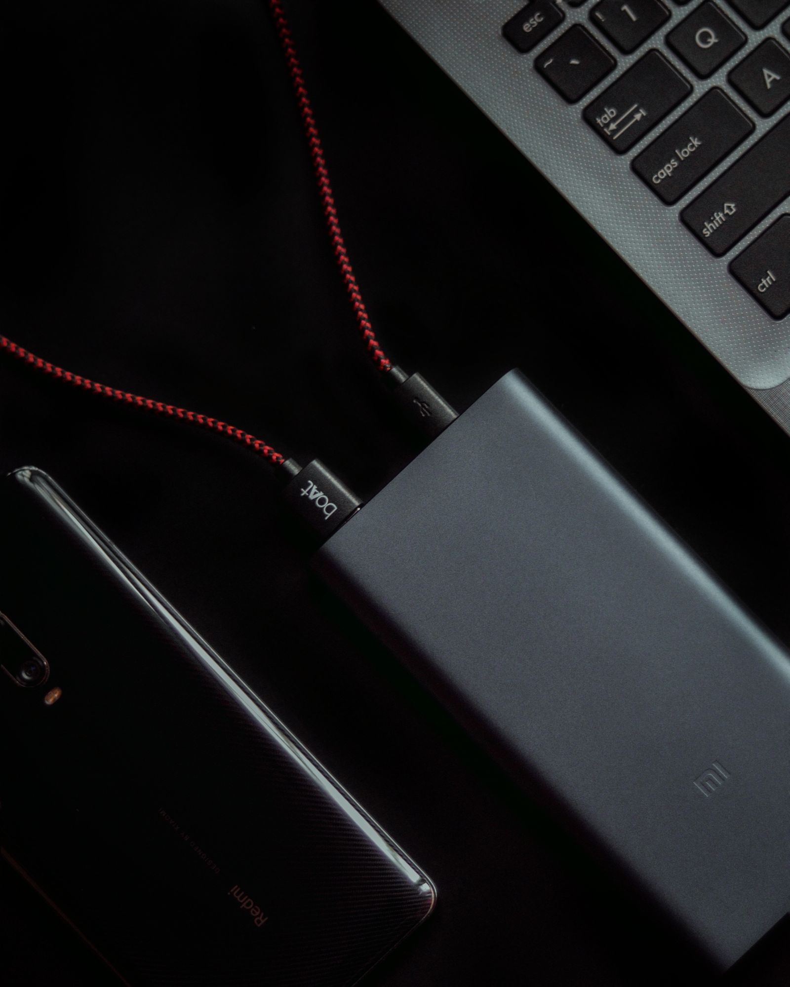 Laptop, smartphone and portable power bank connected by charging cables