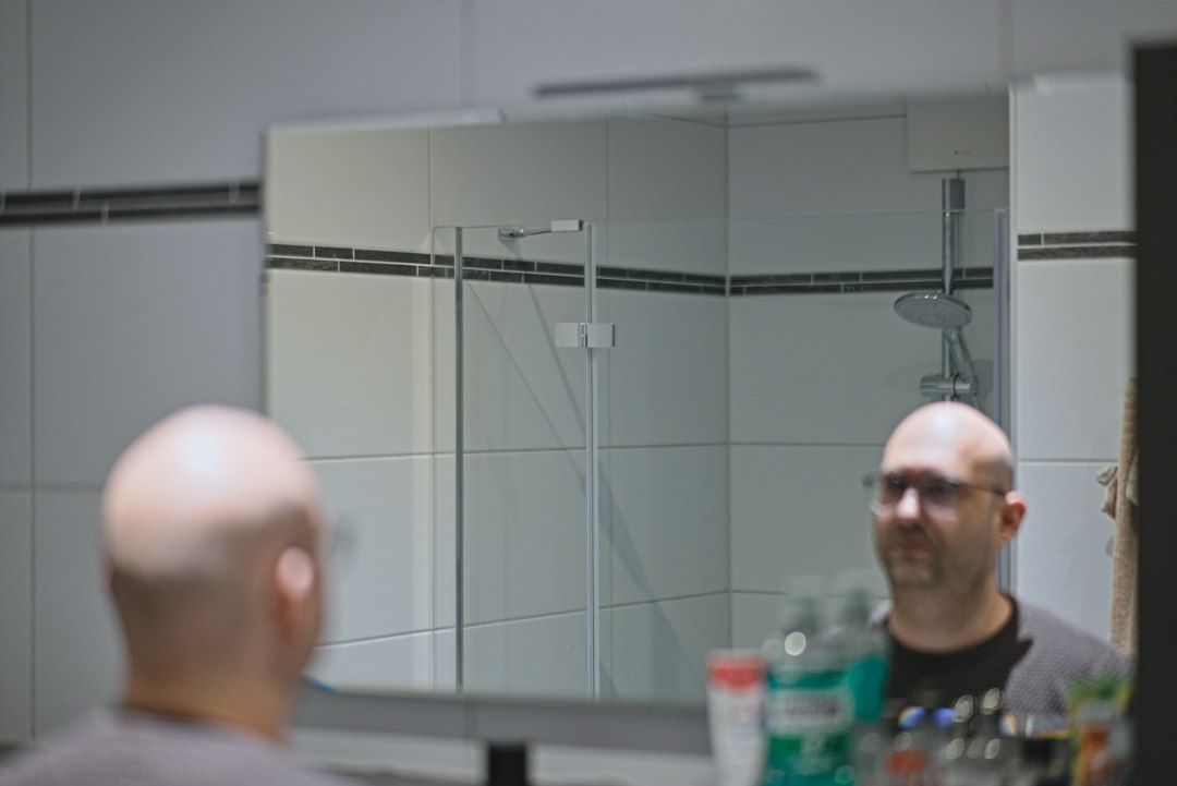 Person at a bathroom mirror illustrating everyday electric shaving context