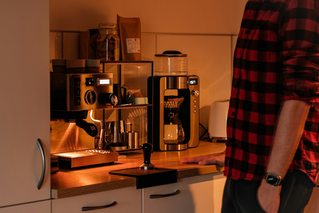 Person beside an espresso machine and grinder illustrating a hands-on home coffee workflow